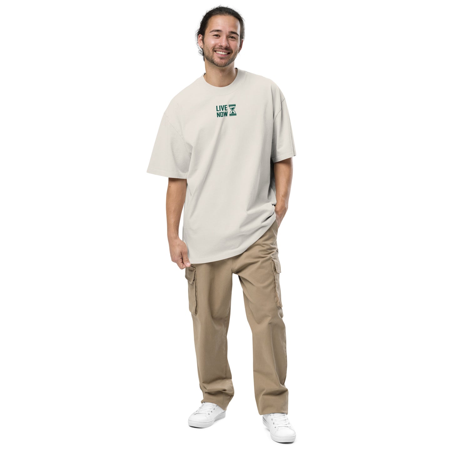 Jeune homme souriant portant un t-shirt oversize beige délavé avec inscription 'LIVE NOW' et pantalon cargo beige